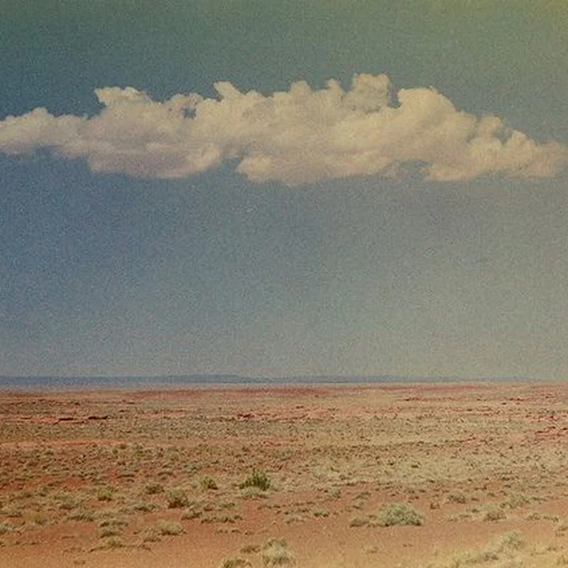 A solitary cloud over an open desert horizon